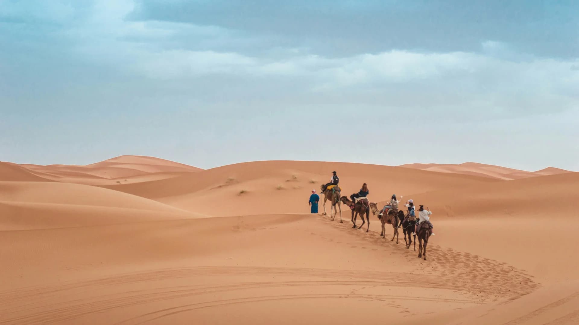 Guida e turisti sui dromedari tra le dune di sabbia del deserto del Sahara in Marocco