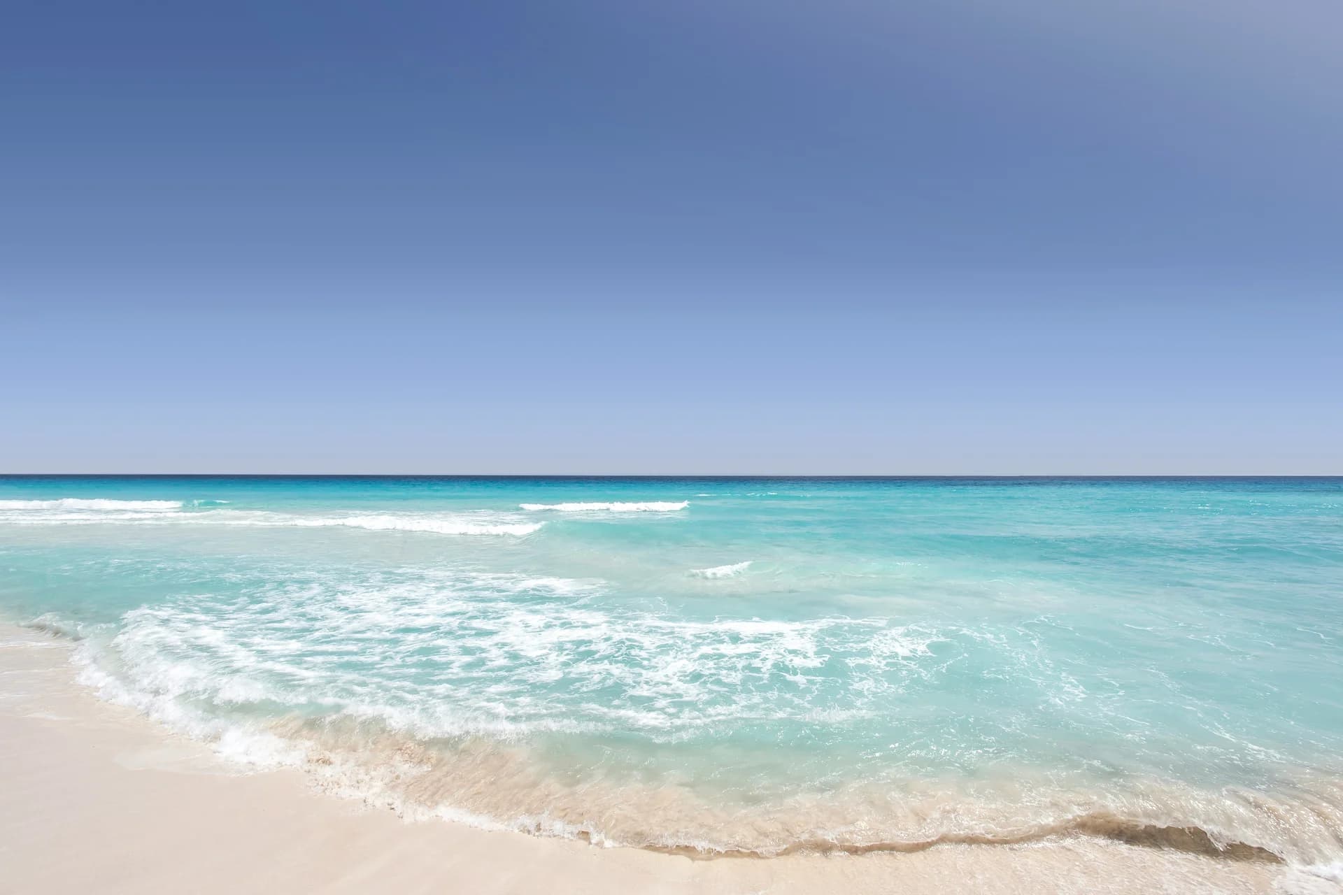 Spiaggia di sabbia bianca e mare turchese sotto un cielo sereno a Cancún, in Messico