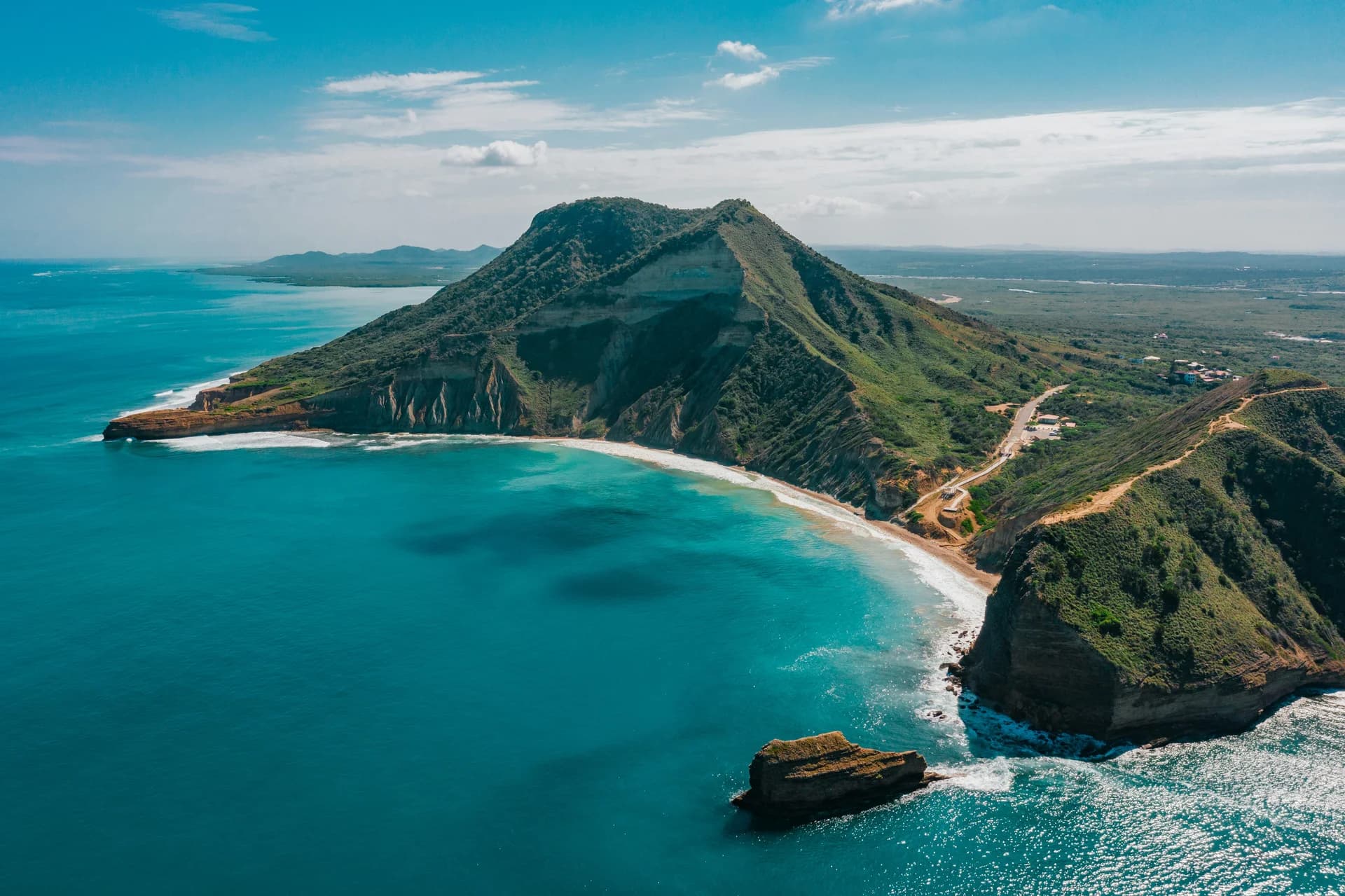 Promontorio montuoso verde, spiaggia e scogliere sull'oceano turchese di Capo Verde